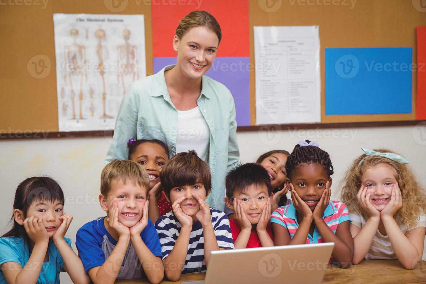 insegnante e alunni che lavorano al computer portatile foto