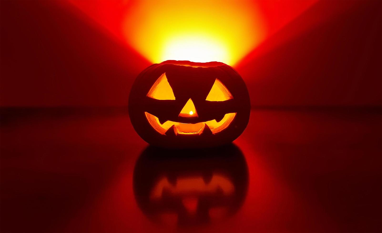 lavorato raggiante zucca con candela dentro nel buio notte e sfocato sfocato sfondo. il indietro parete evidenziato nel giallo rosso pendenza triangolo al di sopra di zucca. Halloween tradizionale jack-o-lantern. foto