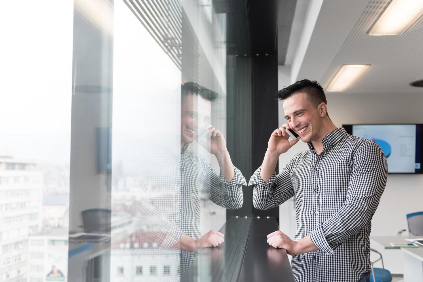 giovane attività commerciale uomo A proposito di su inteligente Telefono a ufficio foto