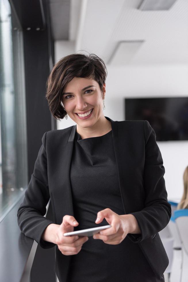 elegante donna utilizzando mobile Telefono di finestra nel ufficio edificio foto