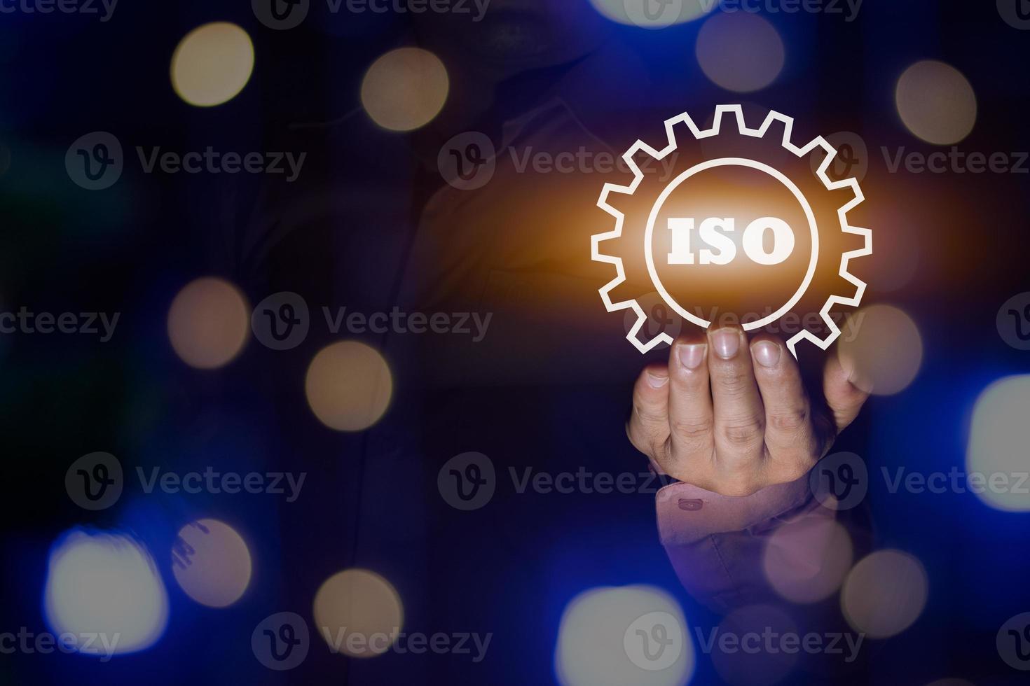 un' uomo d'affari Tenere il iso certificato icona, iso in lavorazione passo bokeh luce, standard qualità documento controllo per organizzazione e industria gestione prodotti, copia spazio per design o testo foto