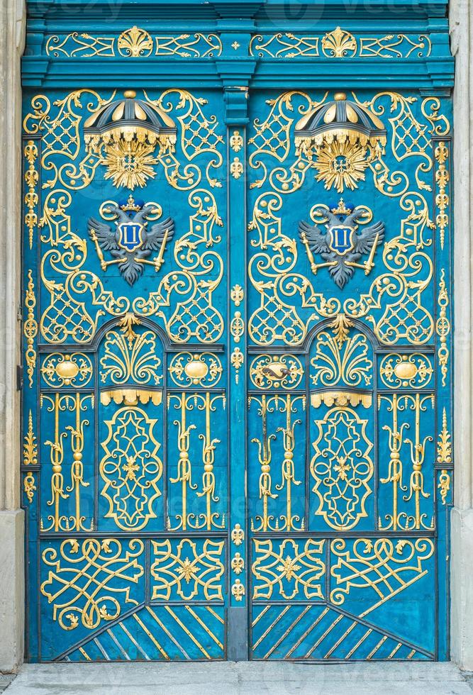 porta blu decorata con ornamenti dorati, maniglia in ferro, portale in pietra foto