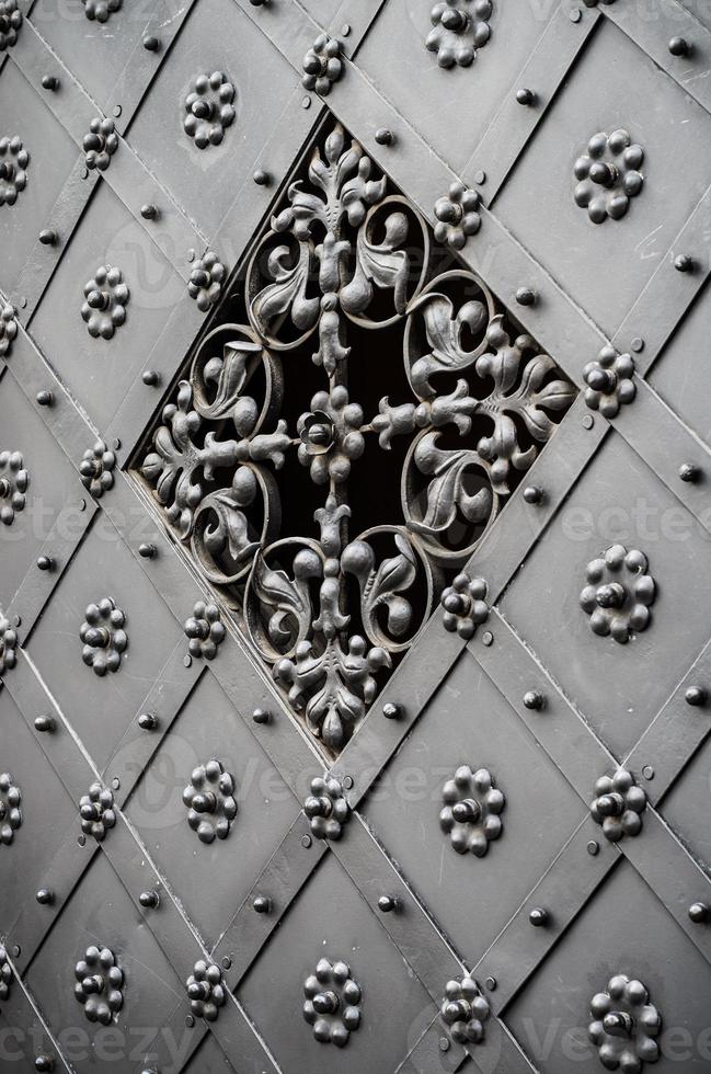 antico portone in ferro riccamente decorato con grata foto