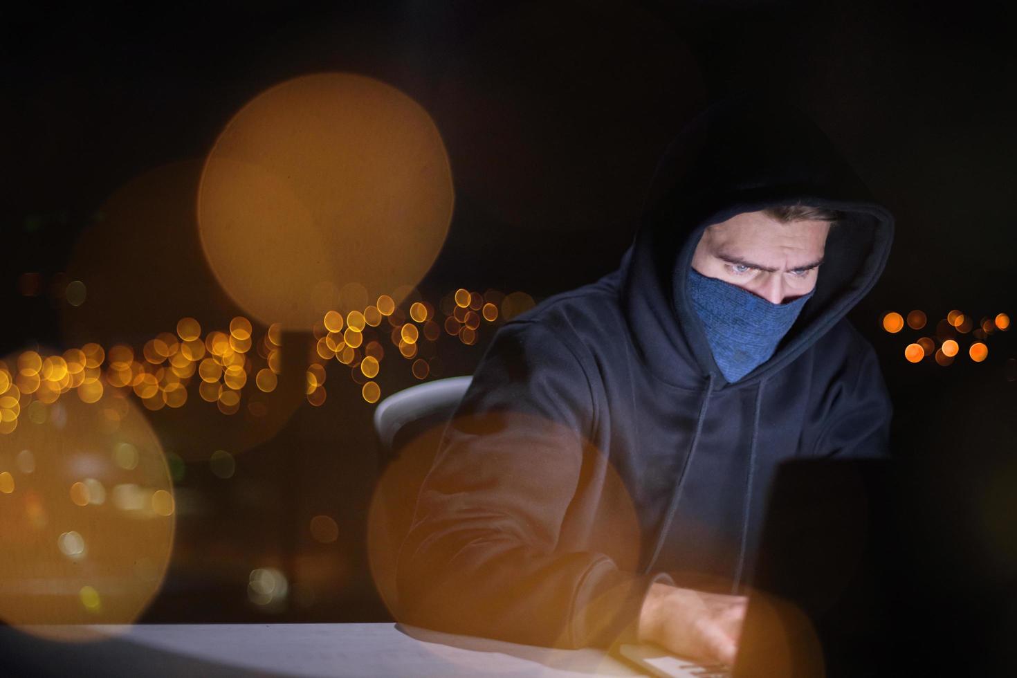 pirata utilizzando il computer portatile computer mentre Lavorando nel buio ufficio foto