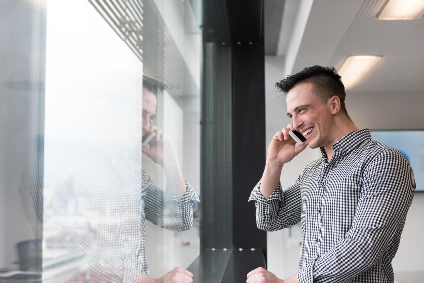 giovane attività commerciale uomo A proposito di su inteligente Telefono a ufficio foto