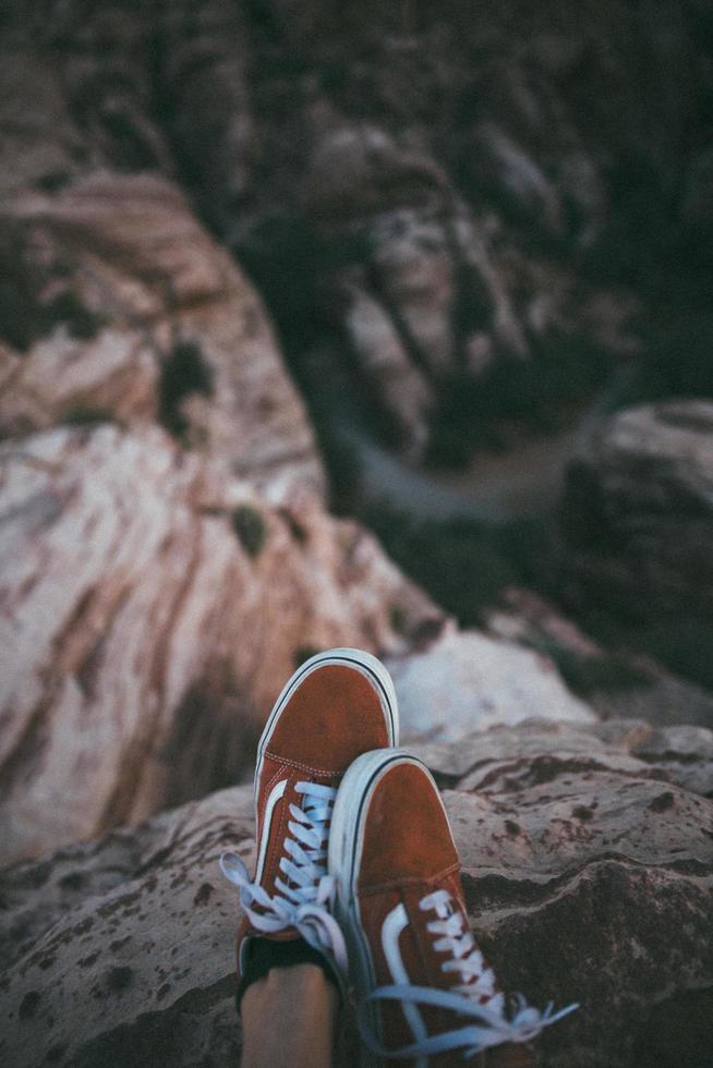 primo piano di scarpe da ginnastica basse vicino a una scogliera foto