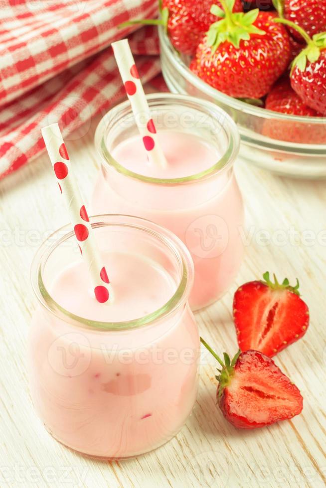 fragola frappè nel il bicchiere vaso su bianca di legno sfondo foto