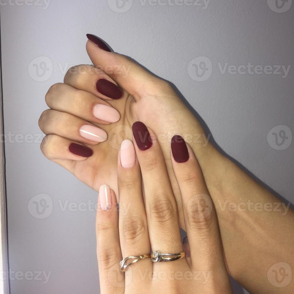 manicure di diverso colori su chiodo. femmina manicure su il mano su grigio sfondo foto