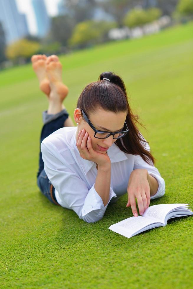 giovane donna che legge un libro nel parco foto