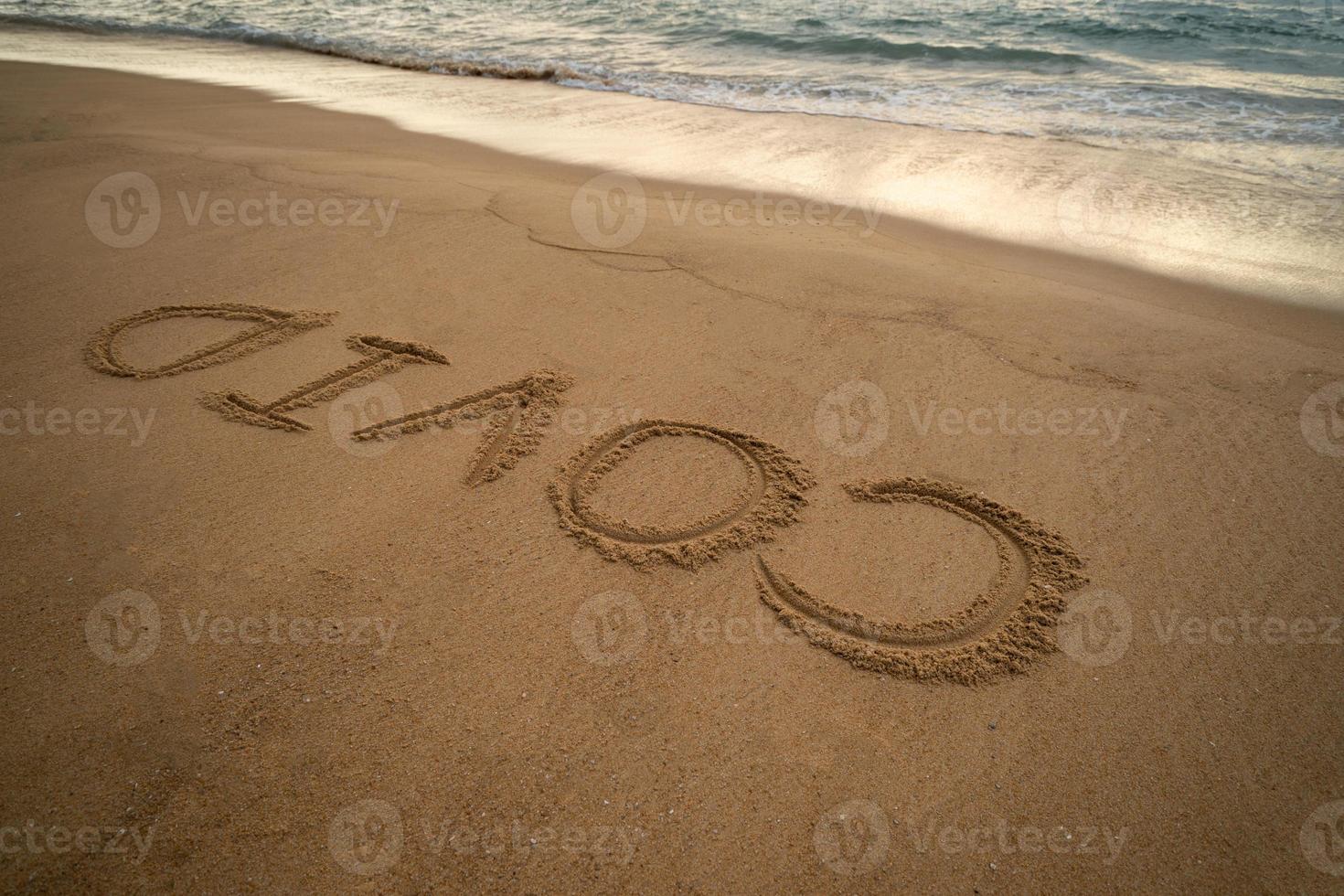 grafia covid su sabbia e schiuma onda su spiaggia. coronavirus concetto. foto