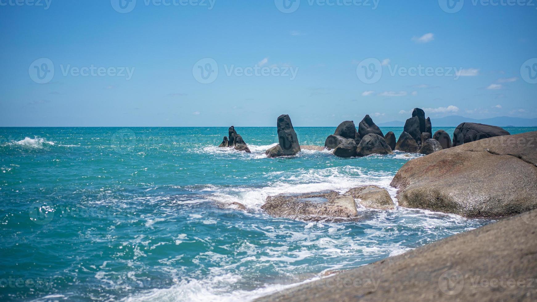 roccioso spiaggia con bianca onde, in profondità blu oceano visualizzazioni e blu cielo. foto