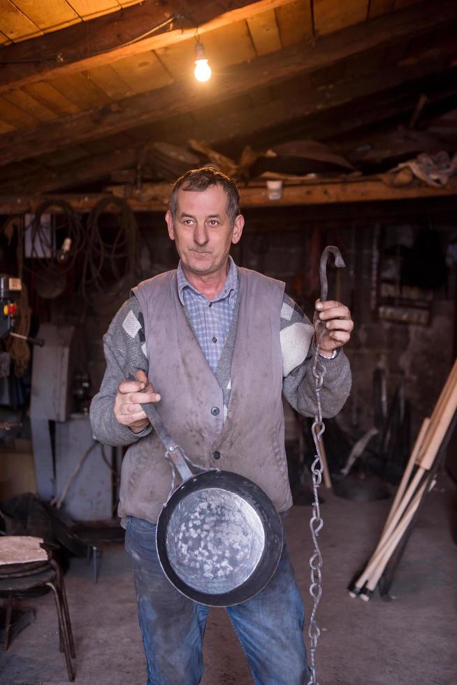 un' maniscalco lavoratore mostrando fatto a mano prodotti pronto per vendita foto