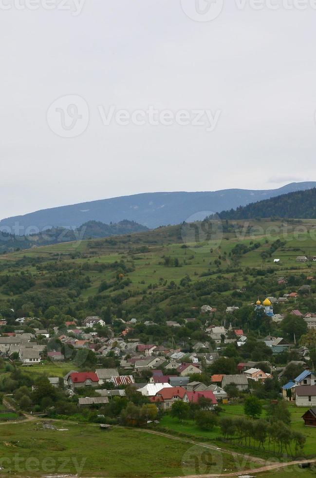 un' bellissimo Visualizza di il villaggio di mezhgorye, carpazi regione. un' lotto di Residenziale edifici circondato di alto foresta montagne e lungo fiume foto