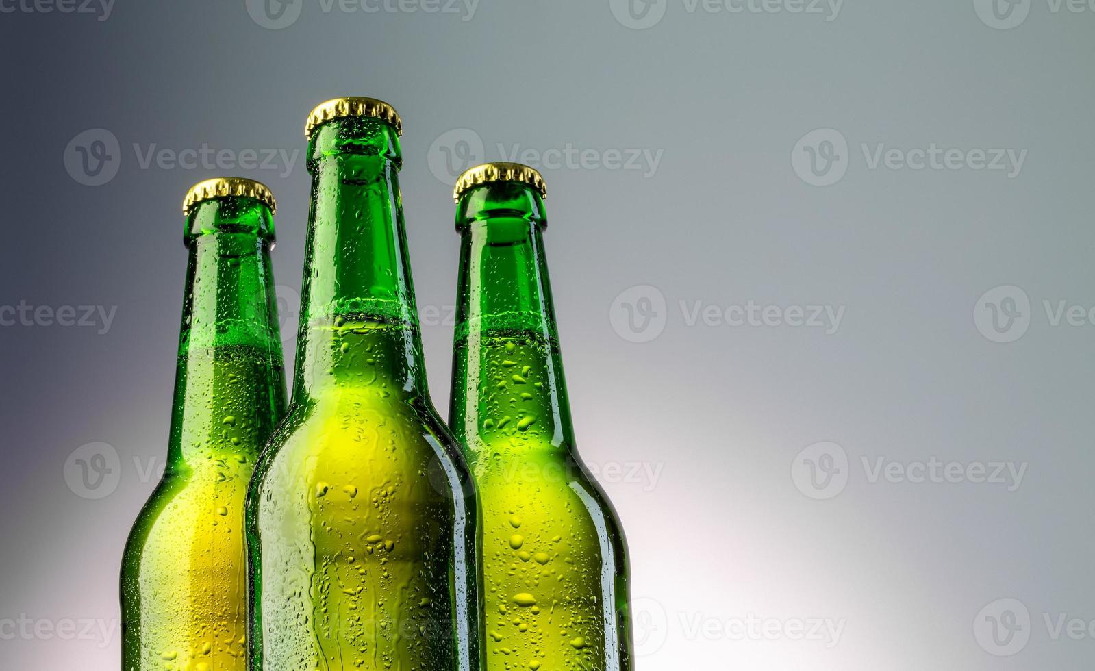primo piano di tre bottiglie di birra verde collo foto