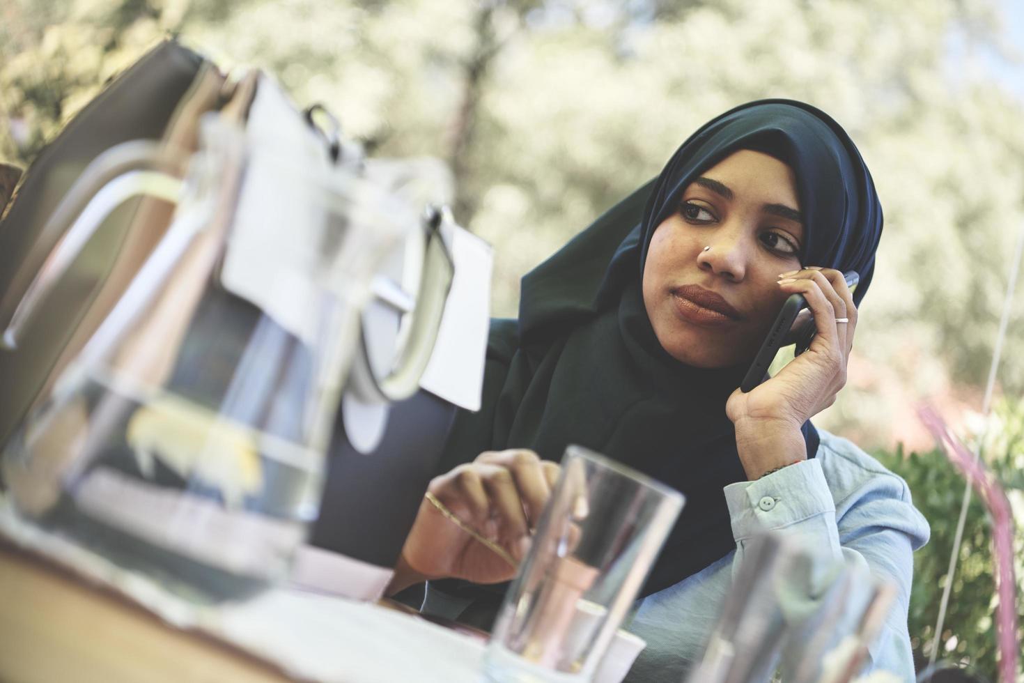 africano donna utilizzando smartphone indossare tradizionale islamico Abiti foto