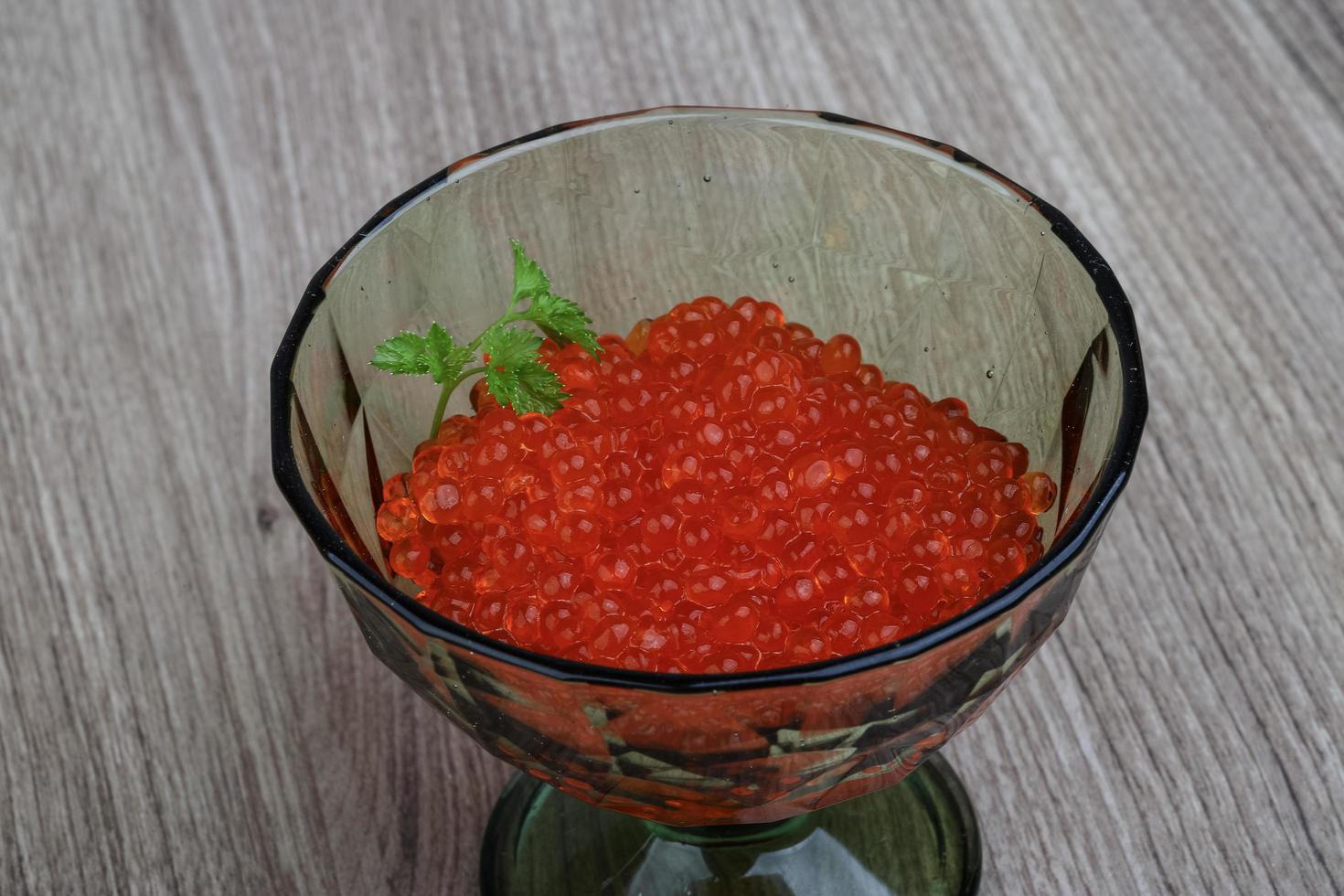 caviale rosso in una ciotola su fondo di legno foto