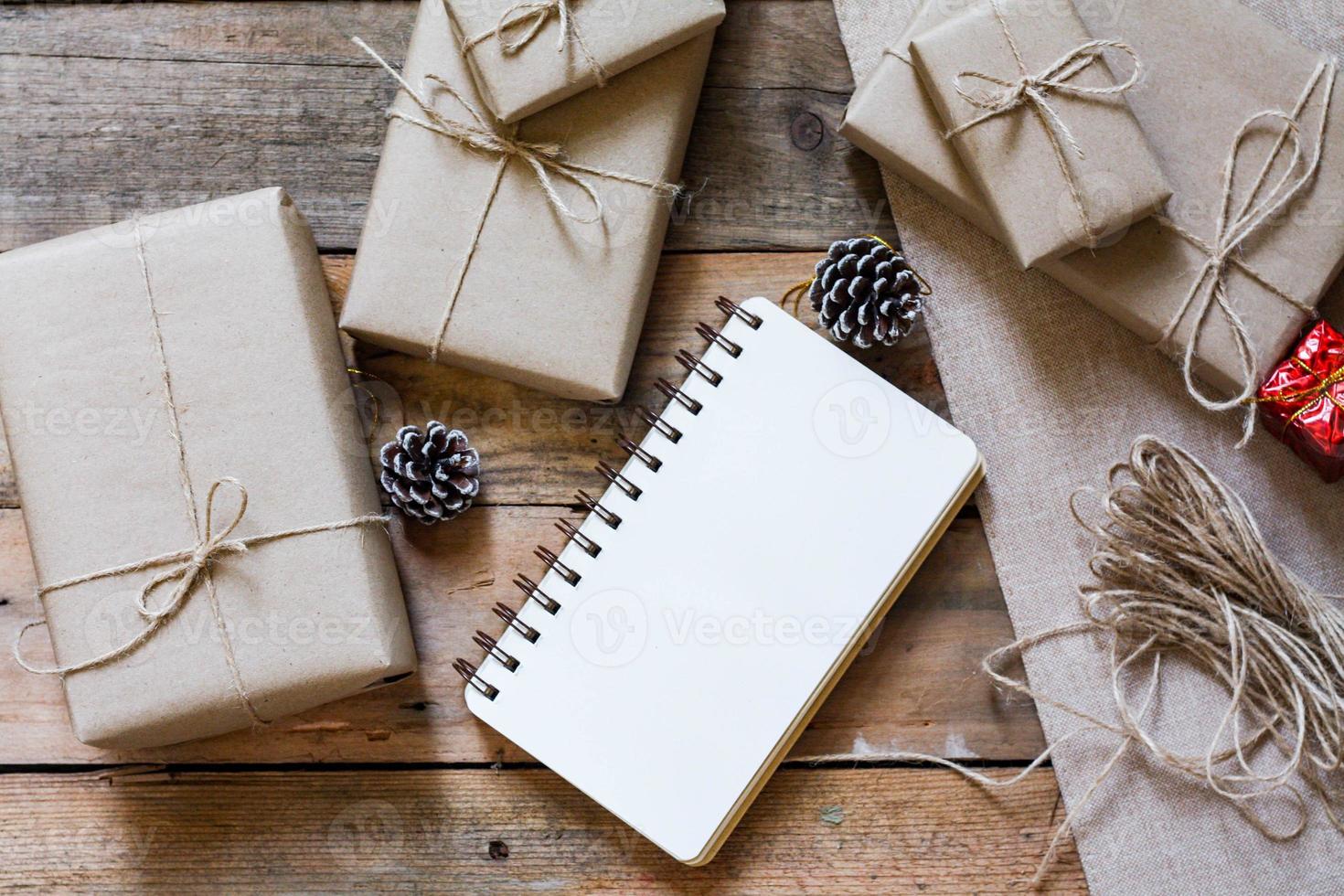 Natale regalo scatola uso Marrone riciclato carta e un' taccuino e pino coni su un' di legno tavolo. foto