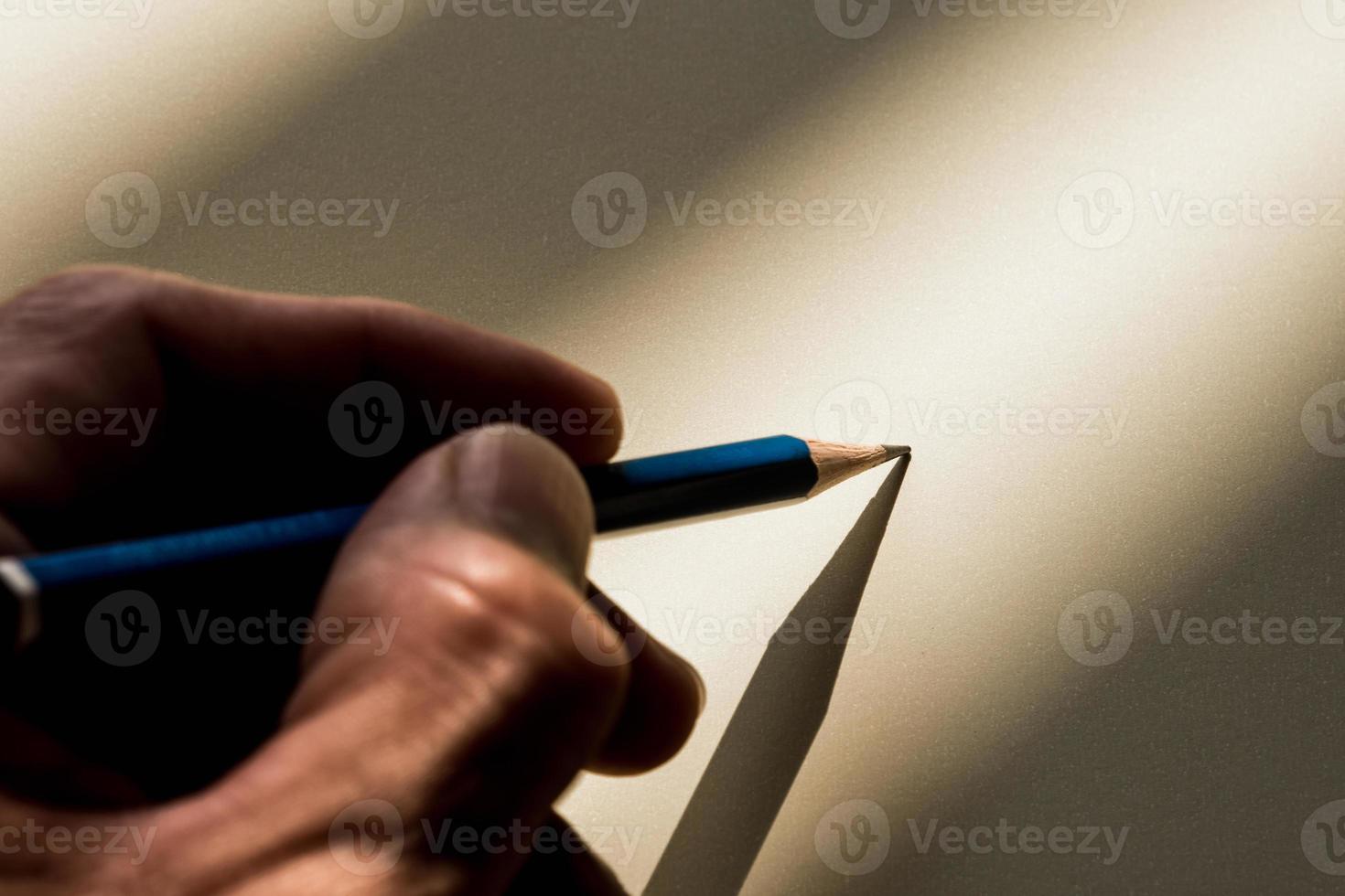 mano umana che tiene matita per scrivere sulla carta in ombra foto