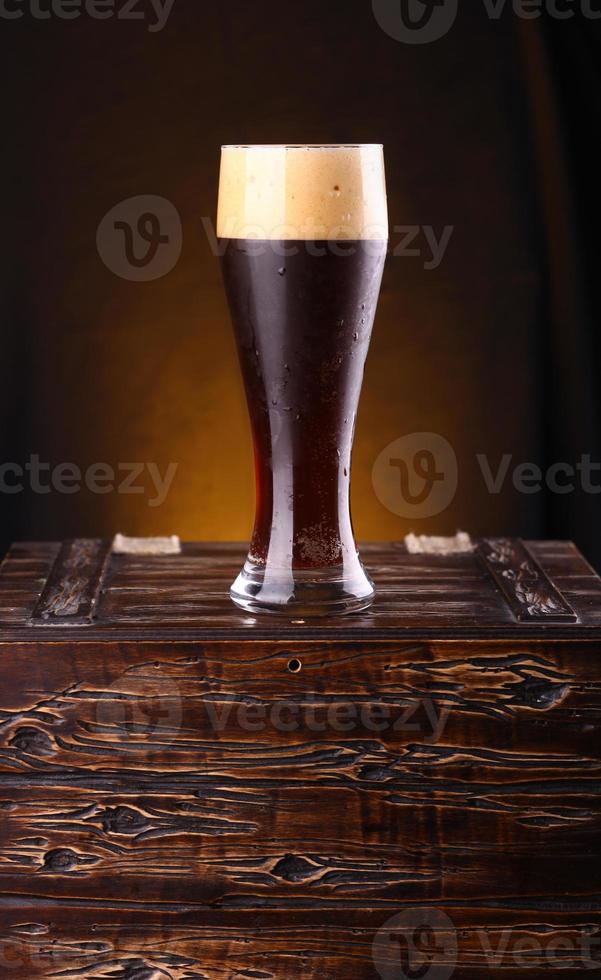 bicchiere di birra scura su una cassa foto