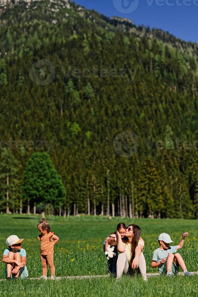 madre seduta con bambini su sentiero nel alpino prato a sottoterra, Austria. foto