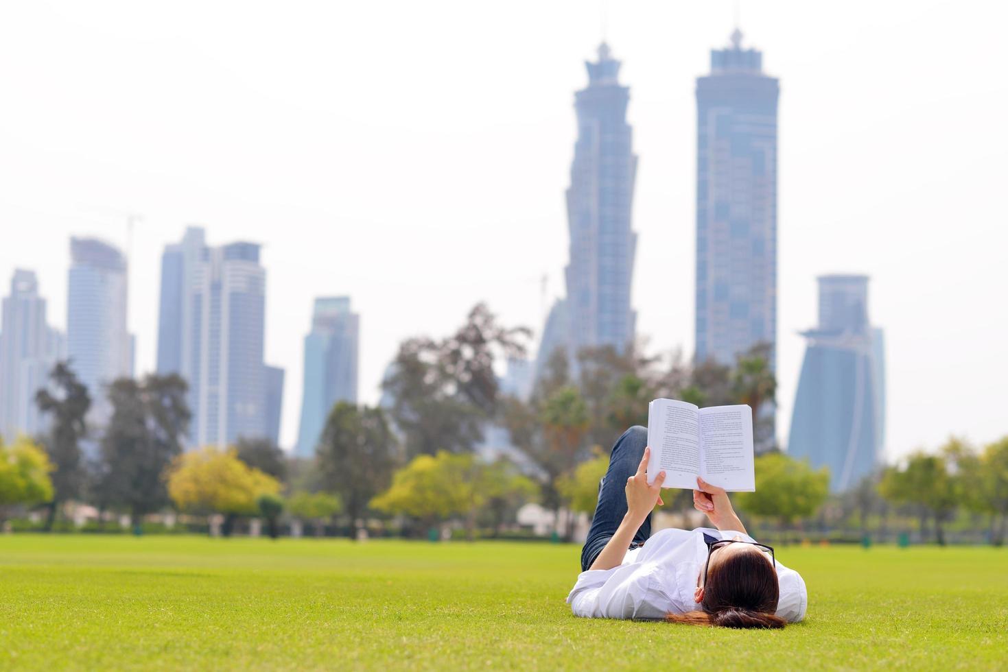 giovane donna che legge un libro nel parco foto