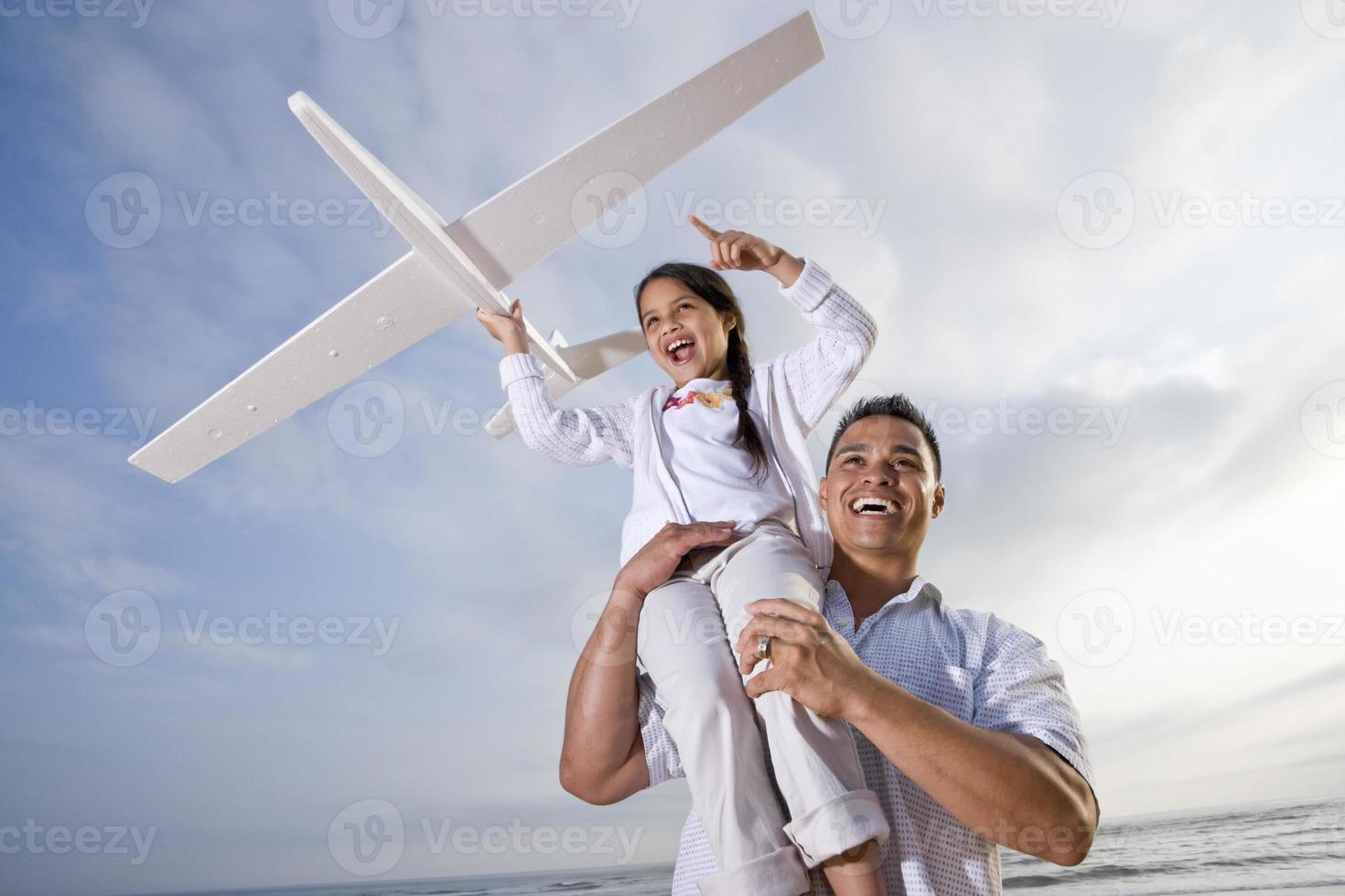 papà ispanico che gioca tenendo la ragazza in alto sulla spalla foto