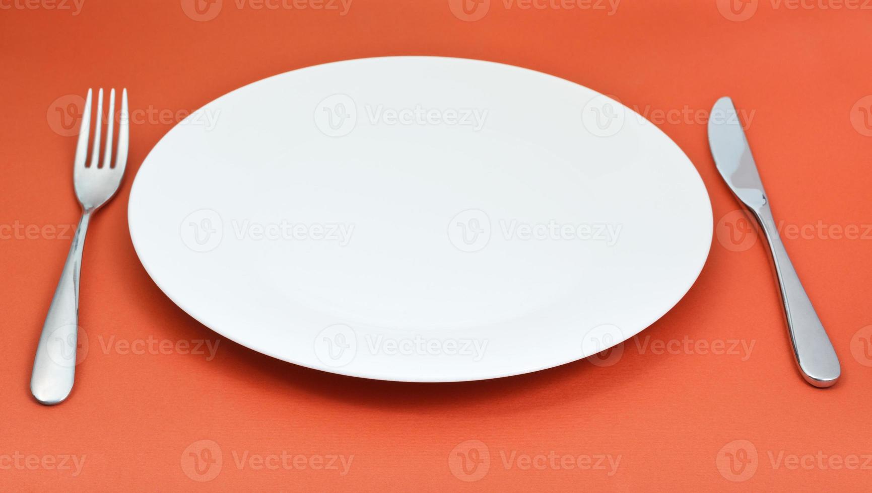 bianca porcellana piatto con forchetta e coltello su rosso foto
