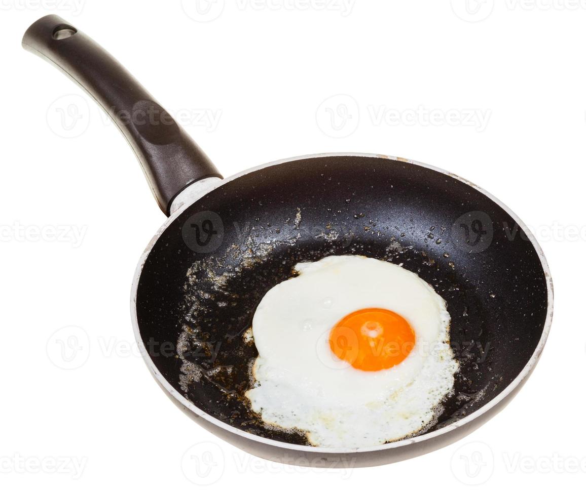 uno fritte uovo nel nero padella isolato su bianca foto