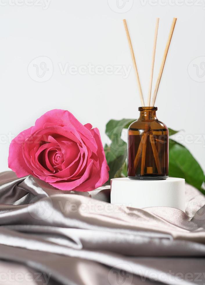 casa aroma diffusore con canna bastoni, rosa fiore profumo. accogliente casa, romantico ambiente, seta raso biancheria da letto fogli. rosa rosa fiore Il prossimo per bicchiere bottiglia con profumato olio. foto