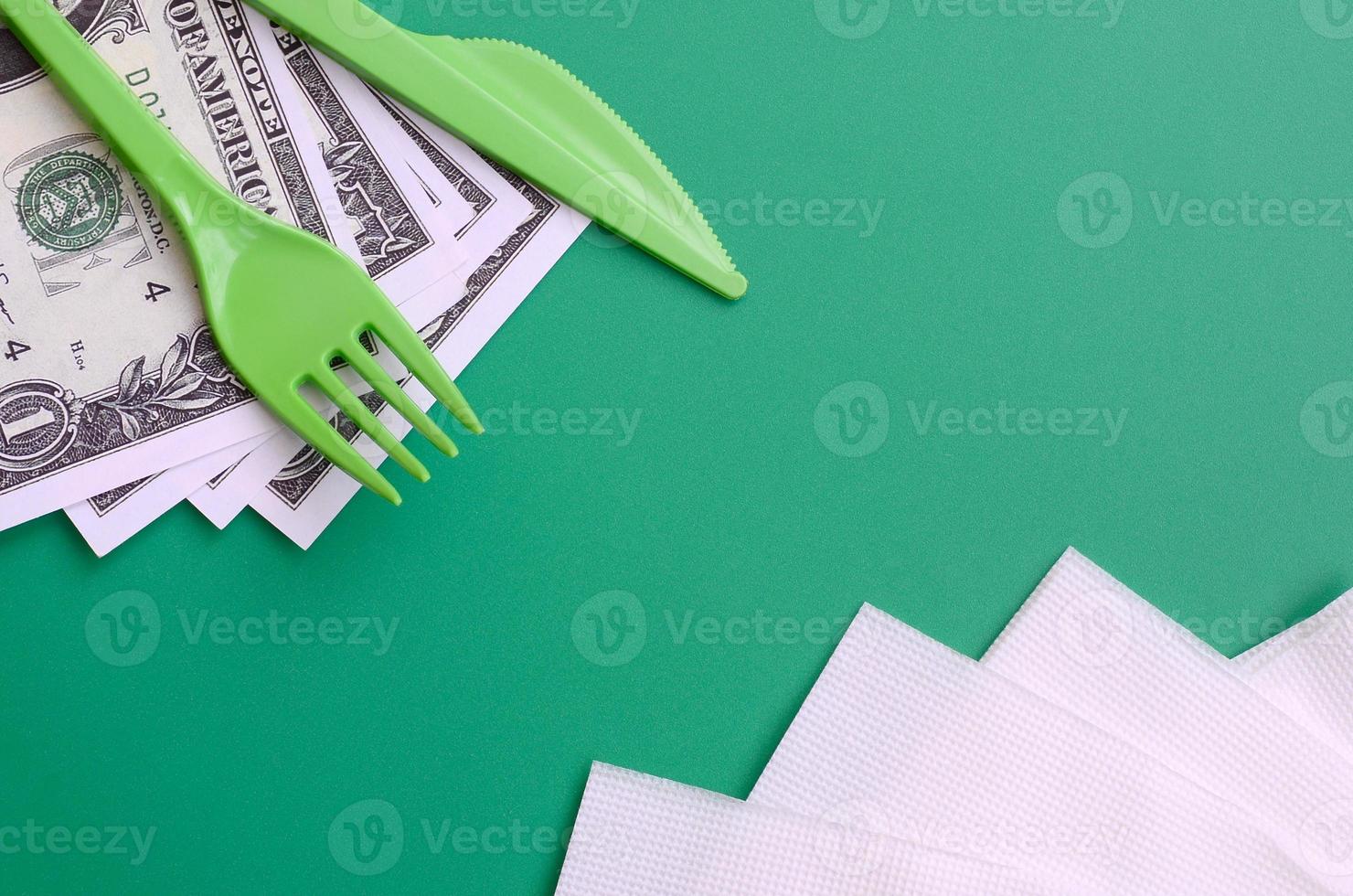 monouso plastica posate verde. plastica forchetta e coltello menzogna su un' piccolo quantità di noi dollari Il prossimo per tovaglioli foto