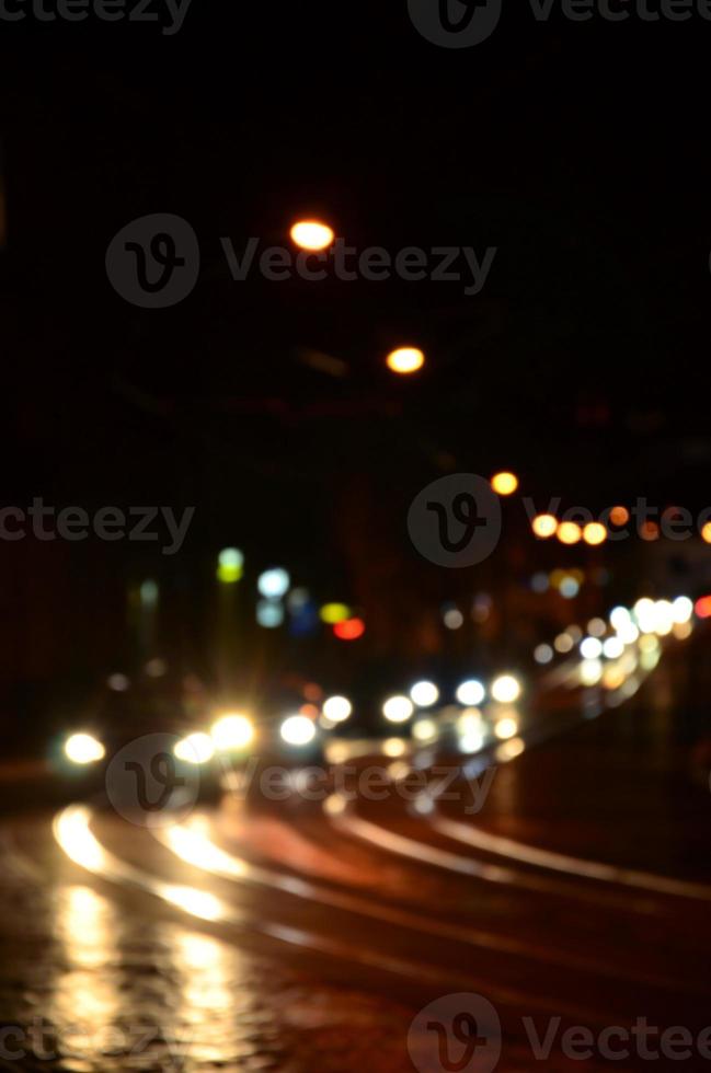 sfocato notte scena di traffico su il carreggiata. sfocato Immagine di macchine in viaggio con luminoso fari. bokeh arte foto