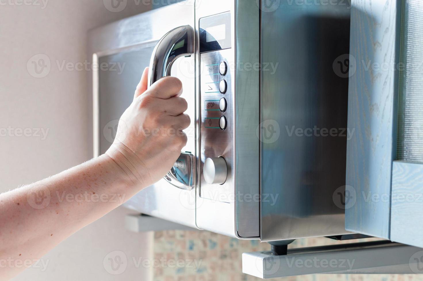 mano si chiude microonde forno per cucinando cibo foto