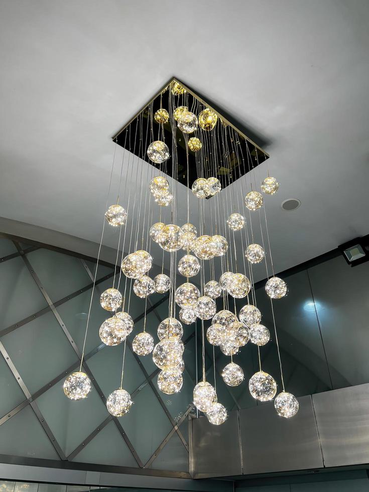 avvicinamento di un' bellissimo cristallo lampadario bellissimo lampadario. lusso costoso lampadario sospeso sotto soffitto foto