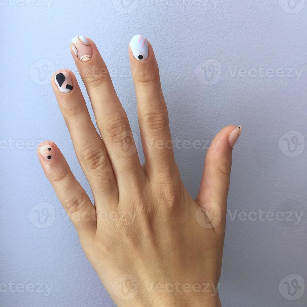 manicure di diverso colori su chiodo. femmina manicure su il mano su blu sfondo foto