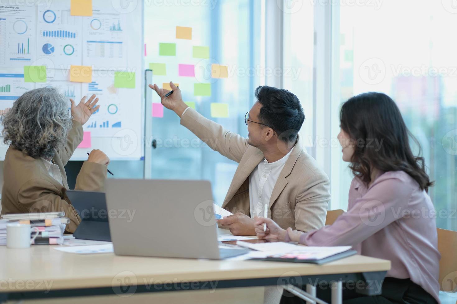 gruppo di asiatico attività commerciale persone discutere insieme nel squadra brainstorming incontro, opera in ritardo notte nel ufficio. aziendale attività commerciale, collaboratore lavoro di squadra, finanziario consulente, o giovane imprenditore concetto foto