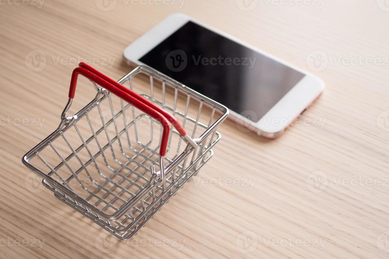 mobile Telefono con cestino su legna tavolo sfondo shopping in linea concetto foto