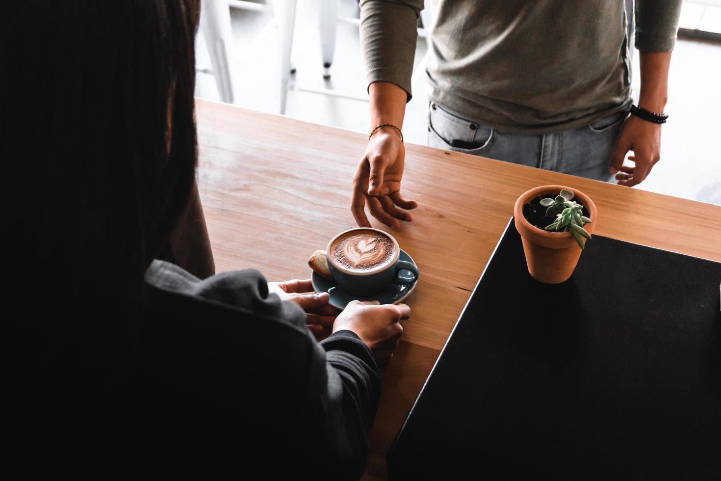 persona dietro il bancone che consegna il caffè al cliente foto