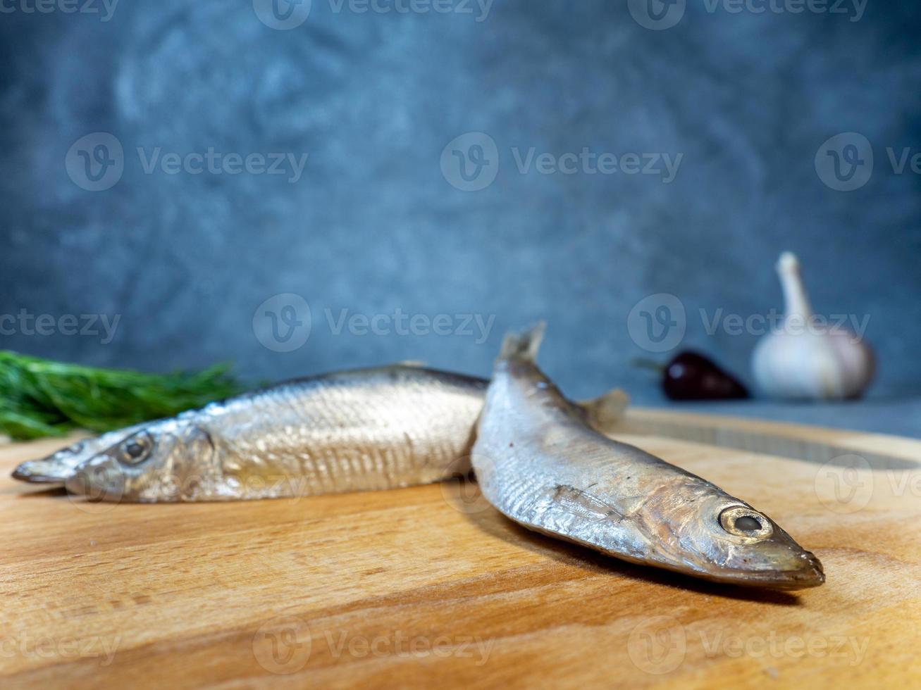 leggermente salato spratto su un' taglio tavola. totale pesce, Pepe, aneto e aglio su il tavolo. foto