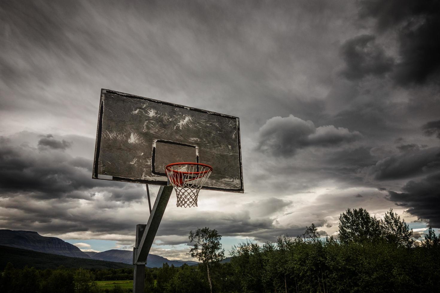 canestro da basket in legno sotto le nuvole scure foto