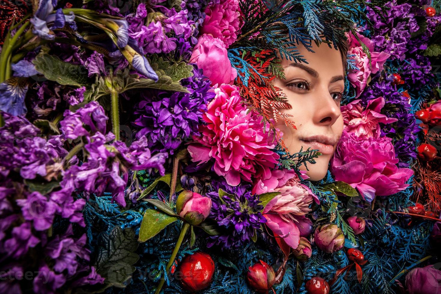 ritratto di ragazza fiaba circondato da fiori e piante naturali. foto