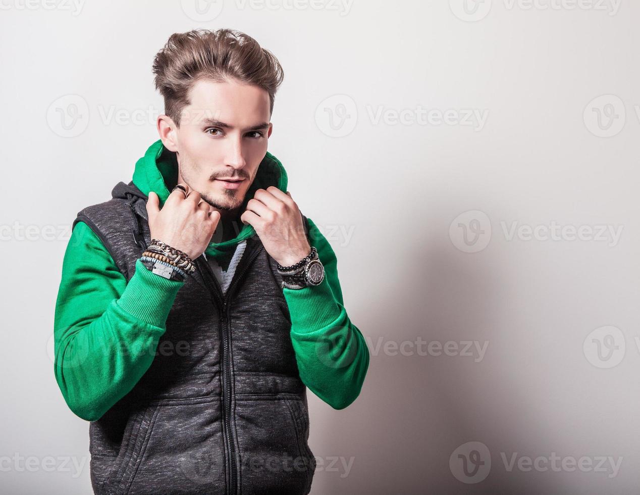 attraente giovane uomo in maglia grigia e maglione verde. foto