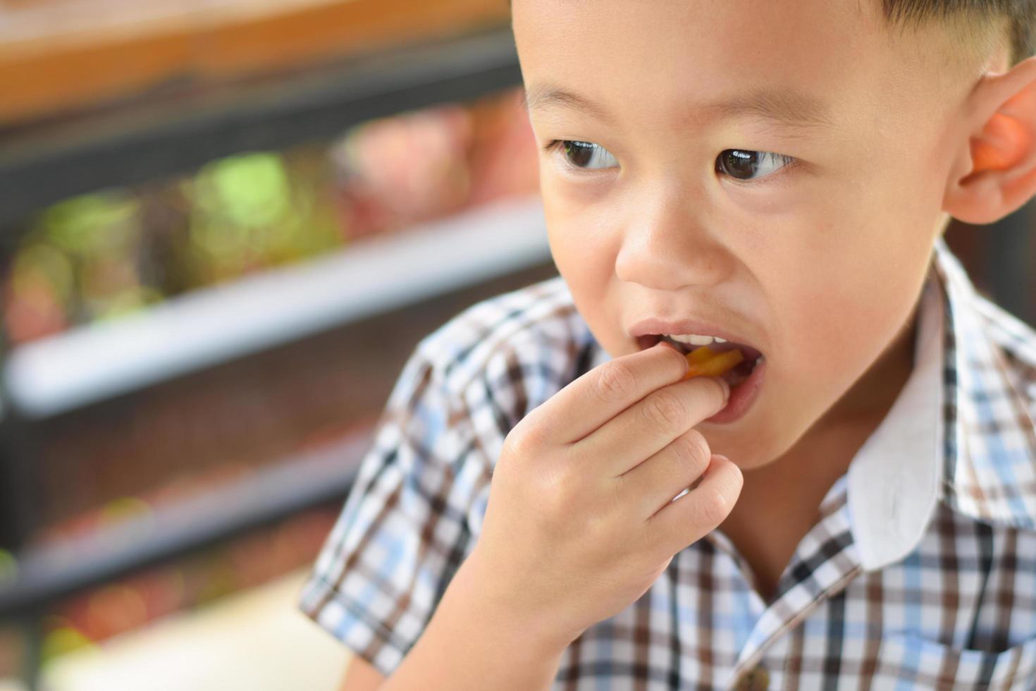 bambino mangiare francese patatine fritte o Patata patatine fritte. foto