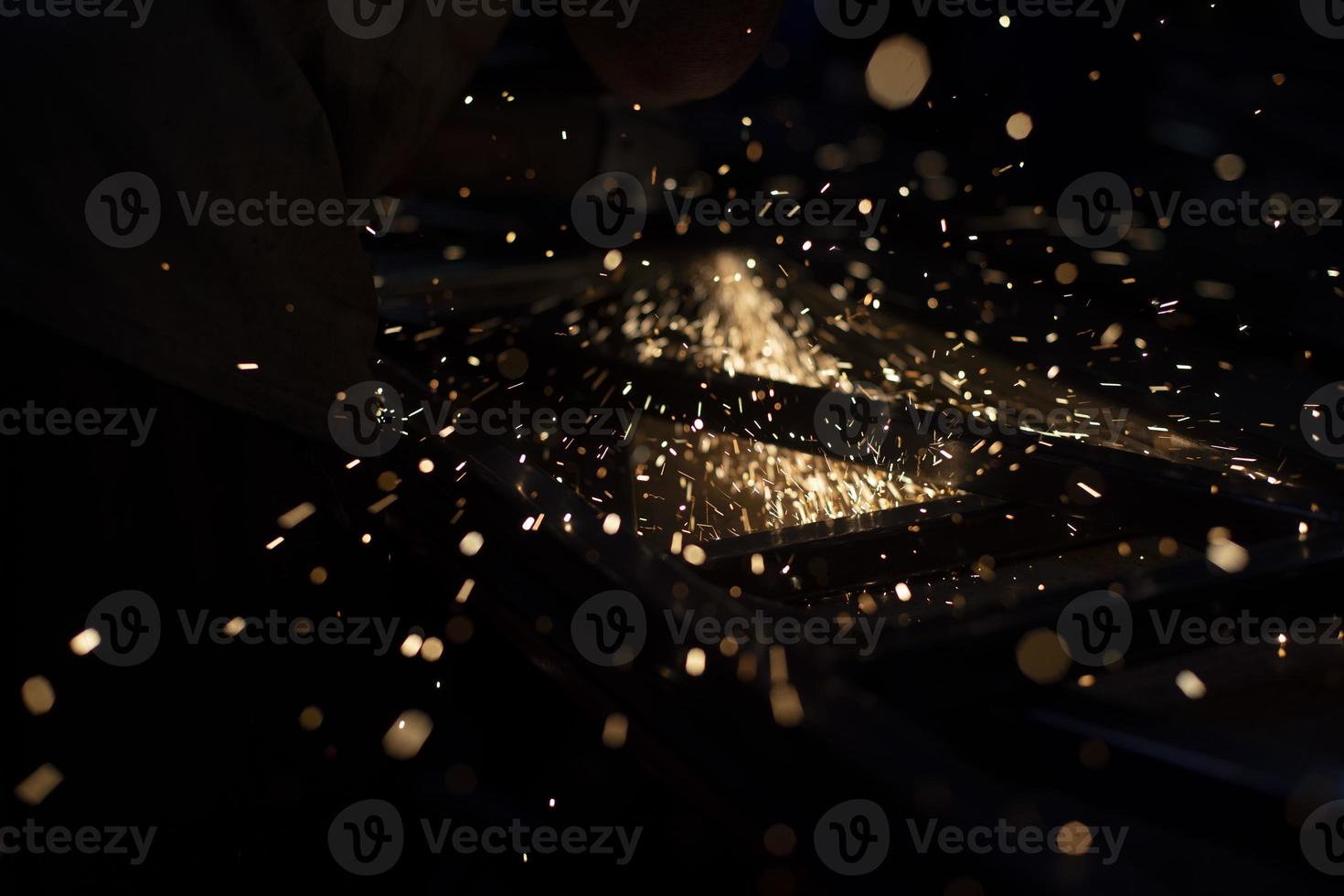 scintille nel scuro. ruscello di luci su nero sfondo. metallo schiacciamento. alto temperatura. foto