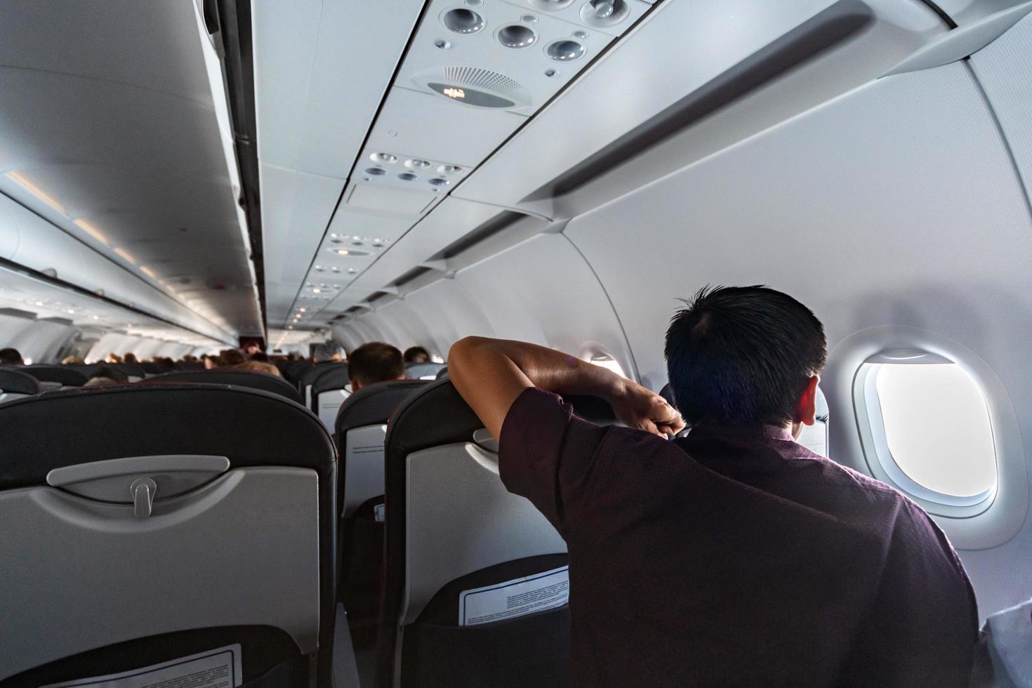 uomo sembra nel aereo finestra. nuovo aereo cabina con confortevole sedili. economia classe volo di nuovo linea aerea senza volo ritardo. foto