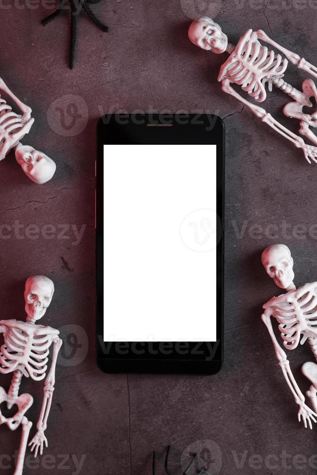 quattro scheletri siamo dire bugie vicino il smartphone su un' buio sfondo. foto