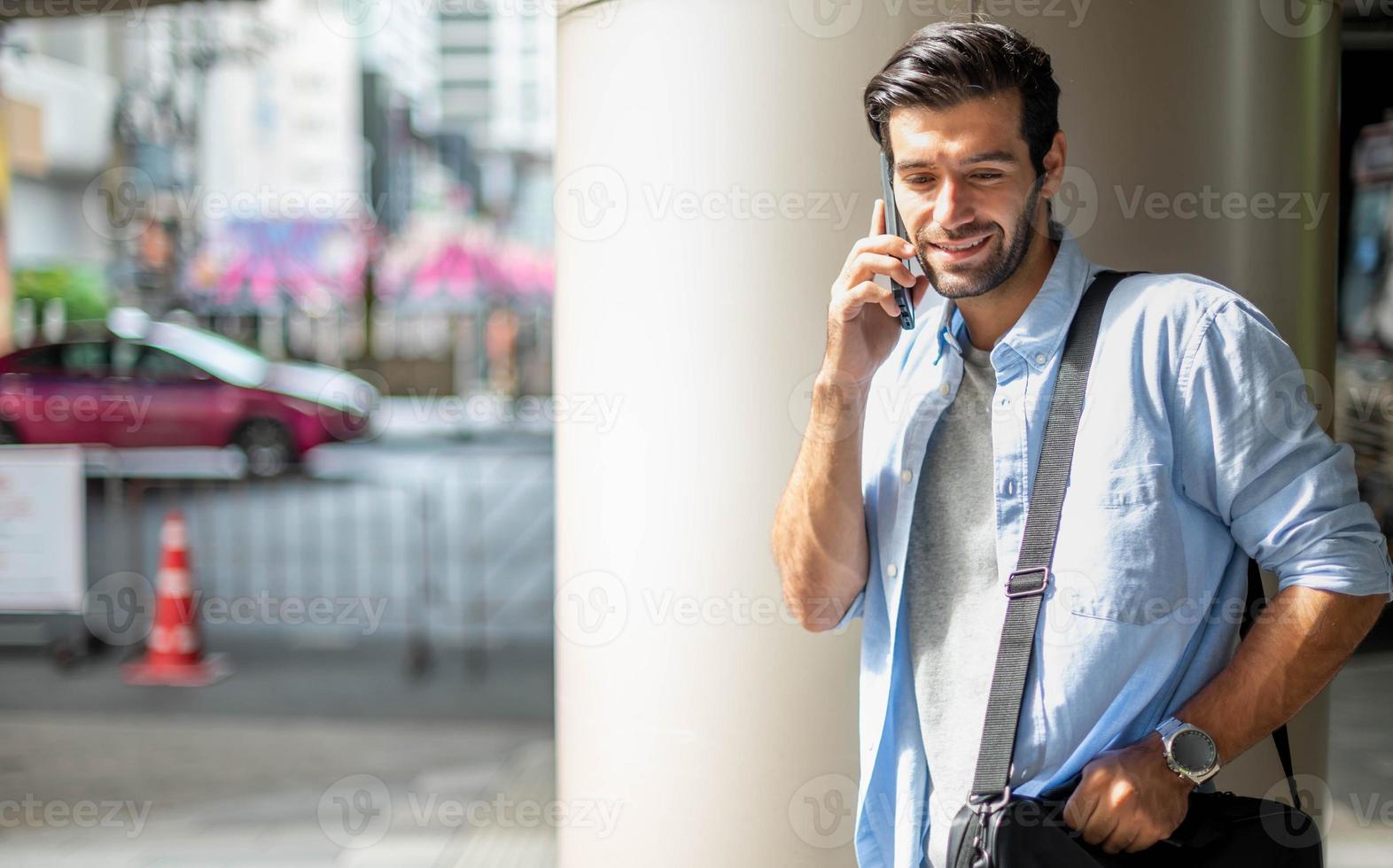 il attività commerciale uomo parlando con inteligente Telefono su loro modo. sensazione contento e rilassante, casuale giovane uomo d'affari indossare completo da uomo giacca e spalla Borsa. foto