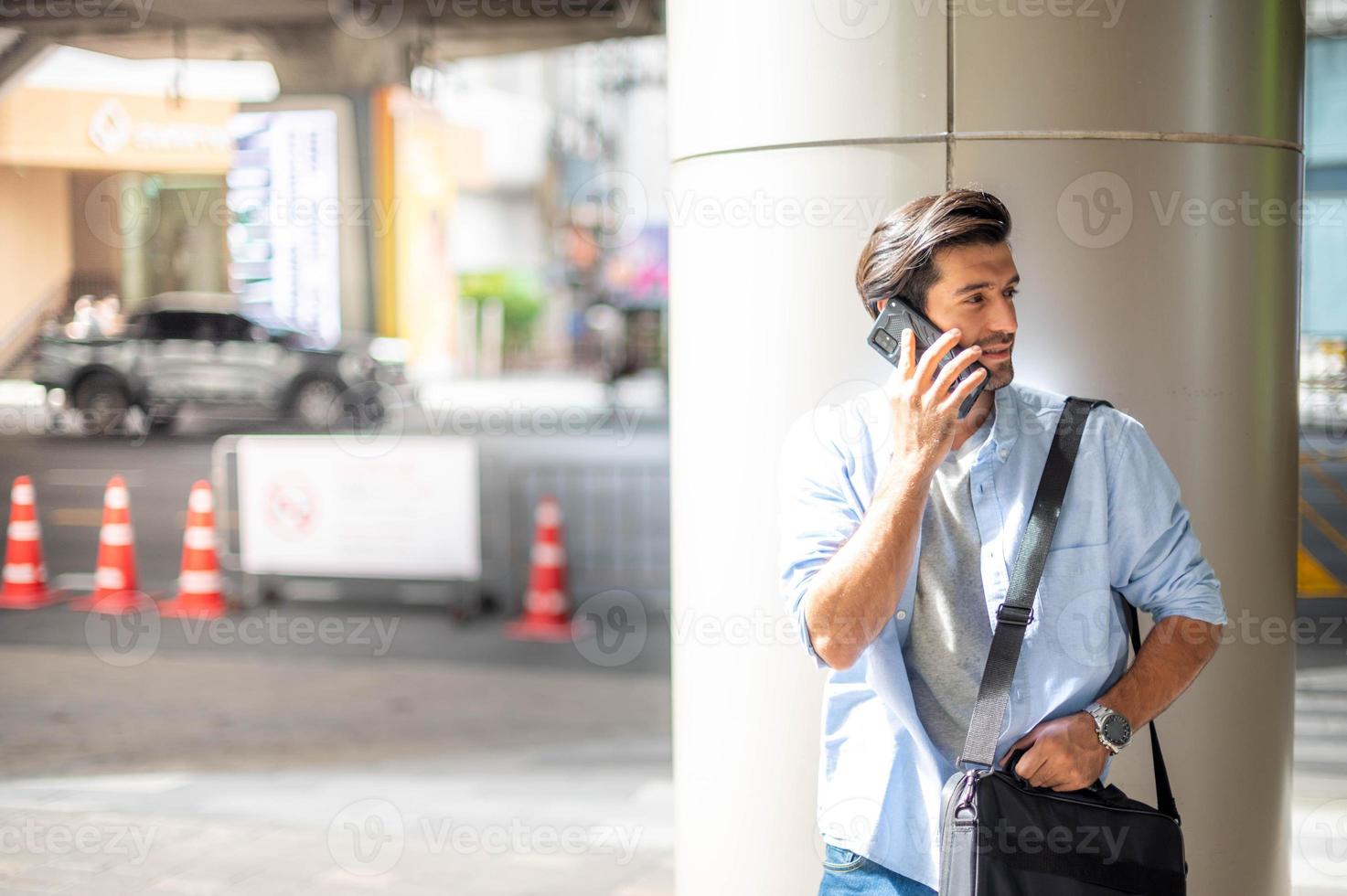 il attività commerciale uomo parlando con inteligente Telefono su loro modo. sensazione contento e rilassante, casuale giovane uomo d'affari indossare completo da uomo giacca e spalla Borsa. foto