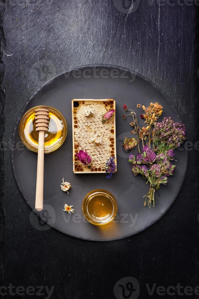 miele ed erbe secche su sfondo scuro foto