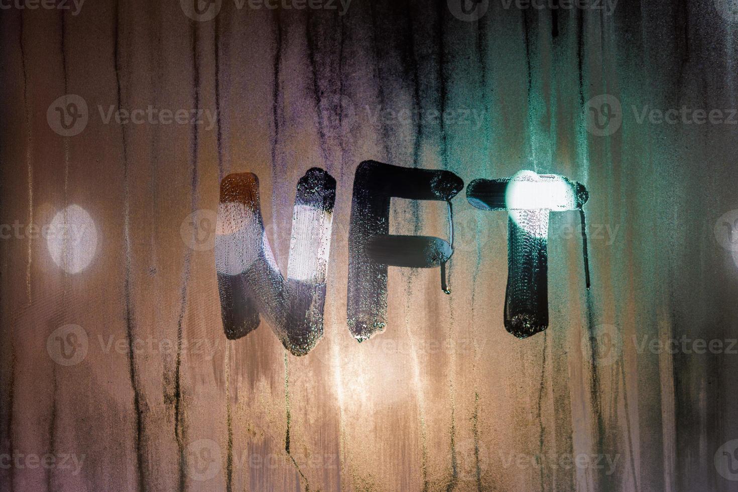 il parola nft - non fungibile gettone manoscritto su nebbioso finestra bicchiere a notte foto