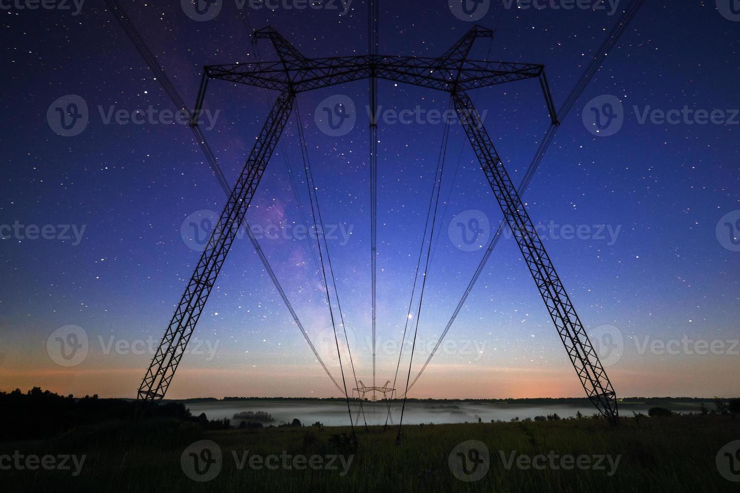 enorme energia linea torri su campo a estate sera foto